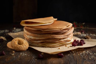 yığın krep katlanmış, gözleme, çilek, Çerezler, pudra şekeri, koyu ahşap masa üzerinde parşömen üzerine karamel şurup