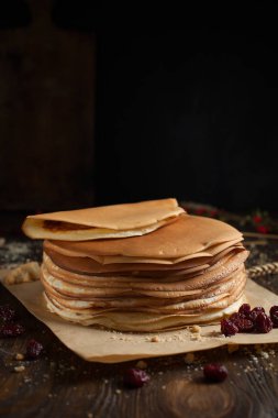 yığın krep katlanmış, gözleme, çilek, Çerezler, pudra şekeri, koyu ahşap masa üzerinde parşömen üzerine karamel şurup