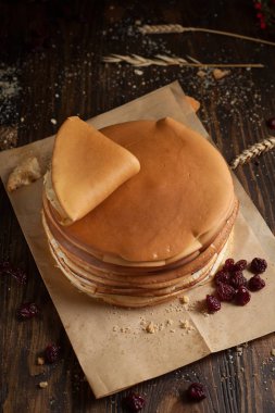 yığın krep katlanmış, gözleme, çilek, Çerezler, pudra şekeri, koyu ahşap masa üzerinde parşömen üzerine karamel şurup