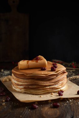 yığın krep katlanmış, gözleme, çilek, kurabiye, pudra şekeri ve koyu ahşap bir masa üzerine parşömen üzerine karamel şurup serpilir