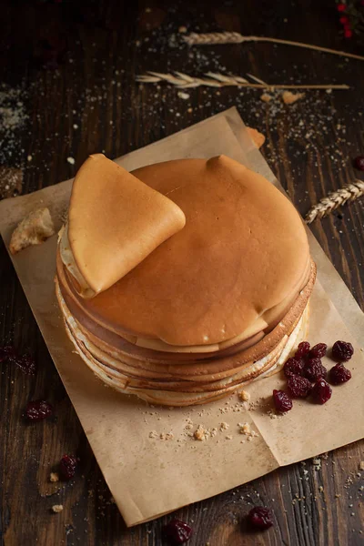 yığın krep katlanmış, gözleme, çilek, Çerezler, pudra şekeri, koyu ahşap masa üzerinde parşömen üzerine karamel şurup