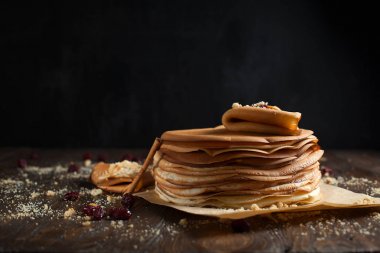 yığın krep katlanmış, gözleme, çilek, kurabiye, pudra şekeri ve koyu ahşap bir masa üzerine parşömen üzerine karamel şurup serpilir