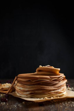 yığın krep katlanmış, gözleme, çilek, kurabiye, pudra şekeri ve koyu ahşap bir masa üzerine parşömen üzerine karamel şurup serpilir