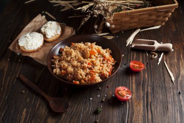 kahverengi bir seramik tabak, kiraz domates ve spikelets buğday, sepet pilav sandviç peynir ve koyu ahşap bir masa üzerinde bir tahta kaşık ile