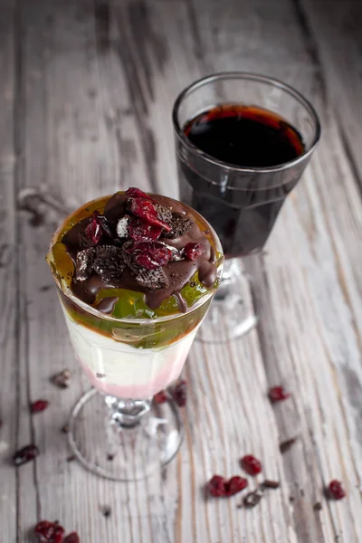 Sobremesa com geléia, chocolate e bagas e um copo de vinho em um fundo de madeira cinza — Fotografia de Stock