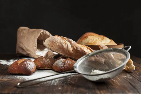 Świeżo upieczony chleb na drewnianym stole na ciemnym tle — Zdjęcie stockowe