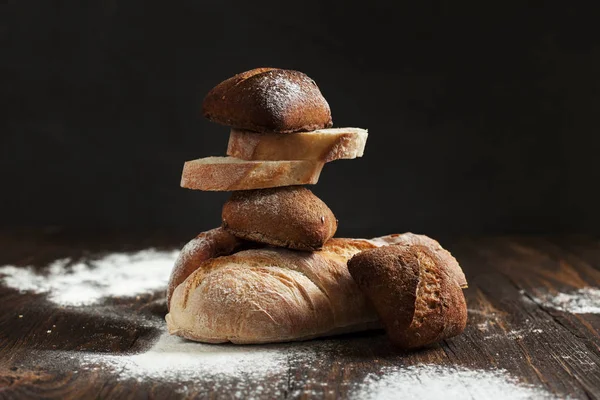Świeżo upieczony chleb na drewnianym stole na ciemnym tle — Zdjęcie stockowe