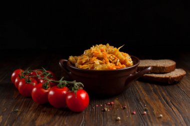 haşlanmış lahana, ekmek ve koyu ahşap bir masa üzerinde kiraz domates