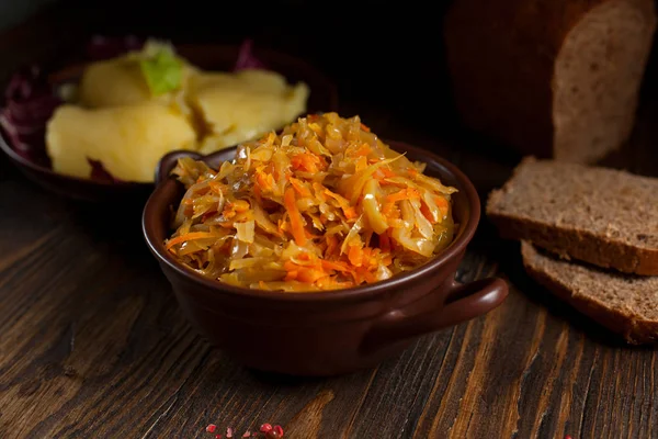 Repolho cozido, pão e tomates cereja em uma mesa de madeira escura Imagem De Stock