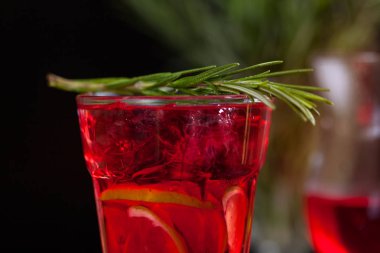 Biberiye karanlık bir arka plan üzerinde bir arka plan üzerine kireç, biberiye ve buz küpleri ile kırmızı renk bir kokteyl ile bir bardak