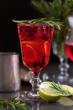 Biberiye karanlık bir arka plan üzerinde bir arka plan üzerine kireç, biberiye ve buz küpleri ile kırmızı renk bir kokteyl ile bir bardak