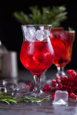kireç, kırmızı meyveler, biberiye ve buz küpleri biberiye karanlık bir arka plan üzerinde bir arka plan üzerinde kırmızı renk bir kokteyl ile bir bardak