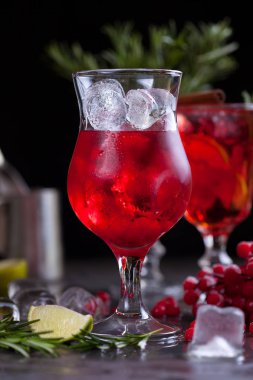 kireç, kırmızı meyveler, biberiye ve buz küpleri biberiye karanlık bir arka plan üzerinde bir arka plan üzerinde kırmızı renk bir kokteyl ile bir bardak