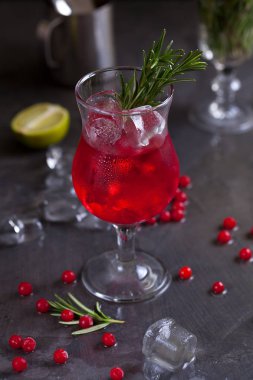 kireç, kırmızı meyveler, biberiye ve buz küpleri biberiye karanlık bir arka plan üzerinde bir arka plan üzerinde kırmızı renk bir kokteyl ile bir bardak