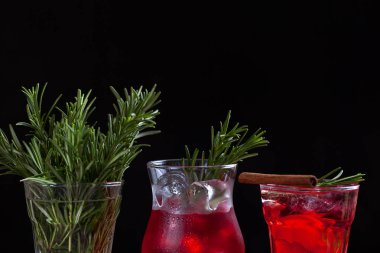 Üç bardak biberiye, kireç ve siyah bir zemin üzerine tarçın ile kokteyller