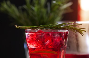 Biberiye karanlık bir arka plan üzerinde bir arka plan üzerine kireç, biberiye ve buz küpleri ile kırmızı renk bir kokteyl ile bir bardak