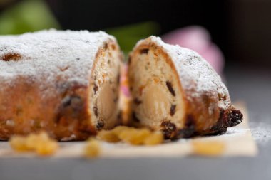 taze pişmiş kek tatlılar, Kuru üzüm ve şekerlenmiş meyve, Pembe Lale ile gri bir tabloda pudra şekeri serpilir