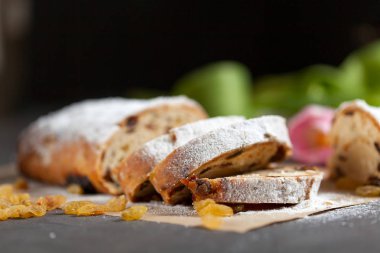 taze pişmiş kek tatlılar, Kuru üzüm ve şekerlenmiş meyve, Pembe Lale ile gri bir tabloda pudra şekeri serpilir