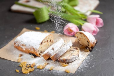 taze pişmiş kek tatlılar, Kuru üzüm ve şekerlenmiş meyve, Pembe Lale ile gri bir tabloda pudra şekeri serpilir