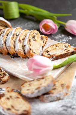 taze pişmiş kek tatlılar, Kuru üzüm ve şekerlenmiş meyve, Pembe Lale ile gri bir tabloda pudra şekeri serpilir