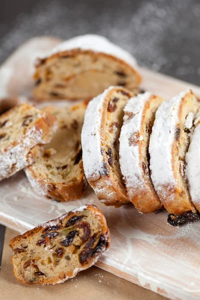 Bolo recém-assado com doces, passas e frutas cristalizadas, polvilhado com açúcar em pó em uma mesa cinza Fotografia De Stock