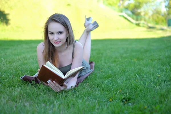 Красива молода жінка читає книгу в парку — стокове фото