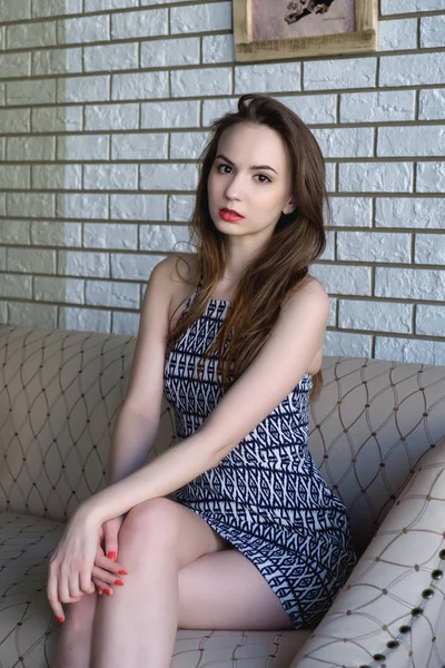 Menina bonita no vestido posando sentado no sofá — Fotografia de Stock