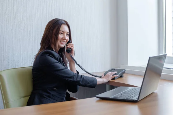 Γυναίκα των επιχειρήσεων εργασίας για το laptop της και μιλώντας στο τηλέφωνο — Φωτογραφία Αρχείου