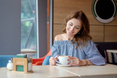 Sabahları restoranda kahve içen bir kadın.