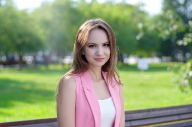 Parkta bir bankta oturan genç ve güzel kadın