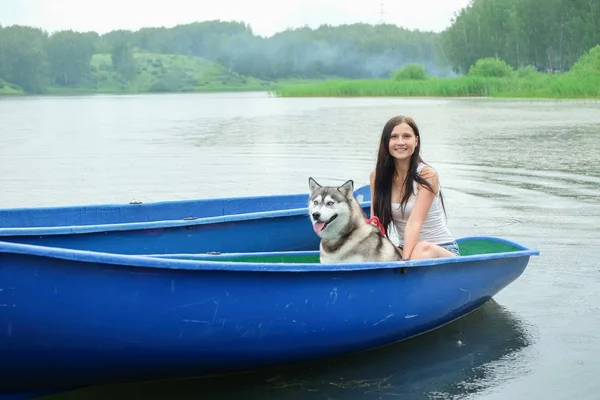 Unga kvinnor och hennes hund husky vila nära sjön i sommar — Stockfoto