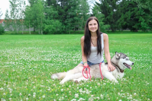 Jovens mulheres e seu cão husky descansando perto do lago no verão — Fotografia de Stock