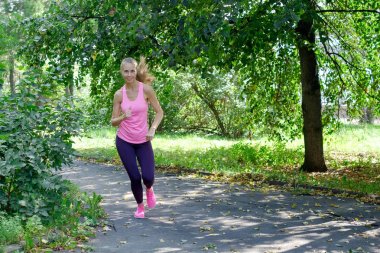 Bahar park yol çalışan kadın koşucu. Egzersiz bir parkta. Güzel kız uygun. Fitness modeli açık havada.