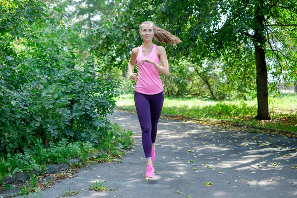 Una donna che corre per la Spring Park Road. Allenarsi in un parco. Bella ragazza in forma. Modello fitness all'aperto . — Foto Stock