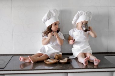 iki küçük baker kız mutfakta bir pabcakes ile çay içiyorlar