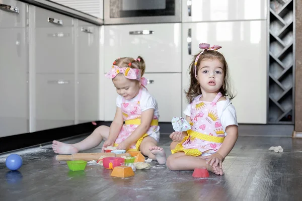 Mutlu kardeşler çocuklar kurabiye pişirir, hamur yoğurur, unla oynar ve mutfakta gülerler.