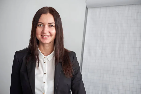 Retrato de jovem mulher de negócios sorridente em pé por flipchart no escritório — Fotografia de Stock