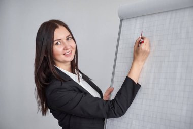 Güzel gülümseyen genç kadın onun bir sunu veya promosyon yaptığı gibi bir boş flipchart Office yazma