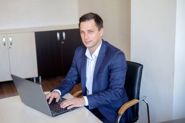 Genç adam masada oturan ofiste çalışan dizüstü bilgisayar ekranına bakarak.