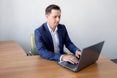 Genç adam masada oturan ofiste çalışan dizüstü bilgisayar ekranına bakarak.