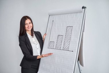 Gülümseyen kadın ofiste marker ile büyük kağıt grafik üzerinde yazma siyah ceketli ve diyagram sunar