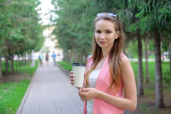 공원에 산책 하는 아름 다운 여자의 초상화입니다. 한 손에 테이크 아웃 음료를 유지. — 스톡 사진