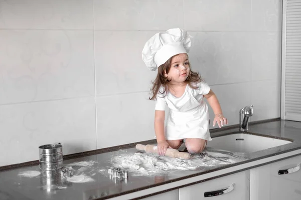 Маленькая девочка делает тесто на кухне со скалкой — стоковое фото