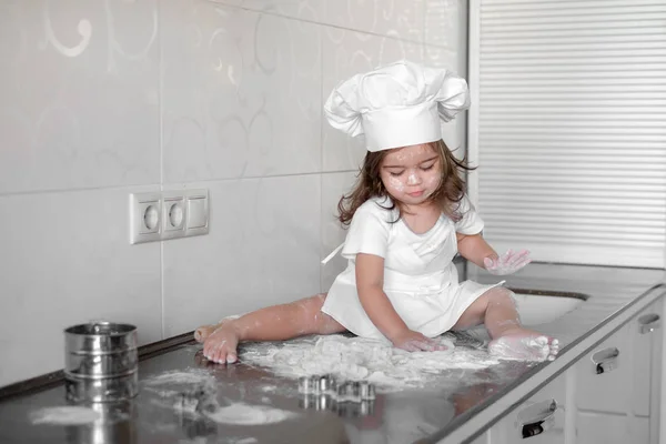 Маленькая девочка делает тесто на кухне со скалкой — стоковое фото