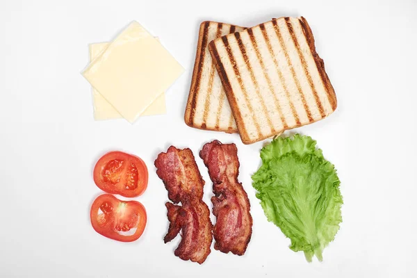 Συστατικά για σάντουιτς. φρέσκα λαχανικά, ντομάτα, ψωμί, becon, τυρί. Απομονωμένα σε λευκό φόντο, το top view, αντίγραφο χώρου — Φωτογραφία Αρχείου