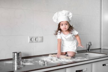 Güzel küçük kız mutfakta yemek yapmayı öğreniyor.