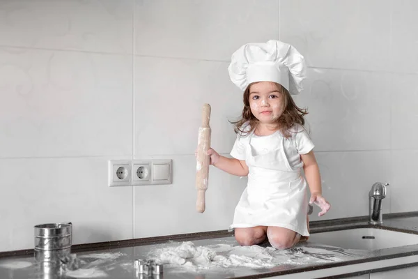 Красивая маленькая девочка учится готовить еду на кухне — стоковое фото