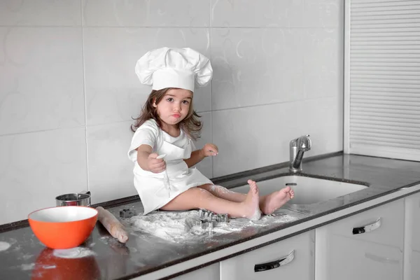 Красивая маленькая девочка учится готовить еду на кухне — стоковое фото