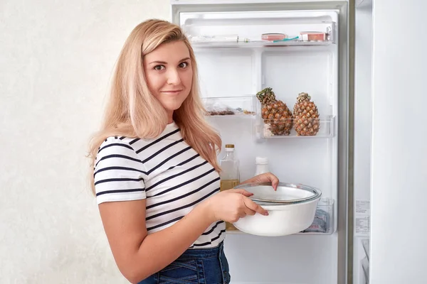Женщина выбирает еду в холодильнике дома — стоковое фото
