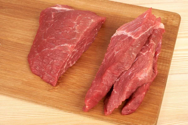 Rått nötkött bit och skivor på trä skärbräda — Stockfoto